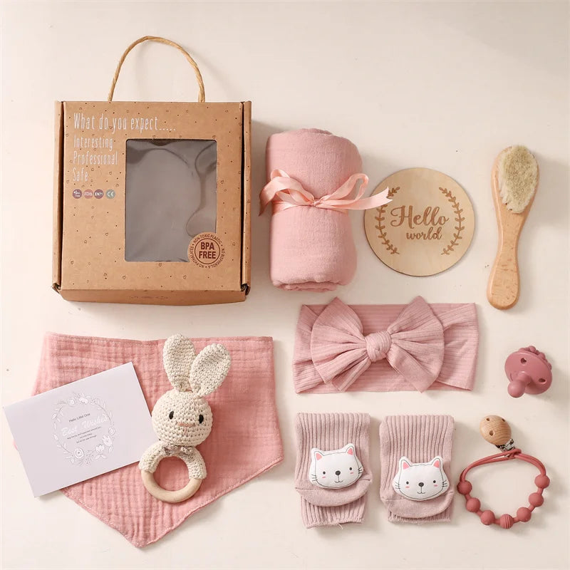 Baby gift set with pink items including a blanket, headband, and toys on a light background.
