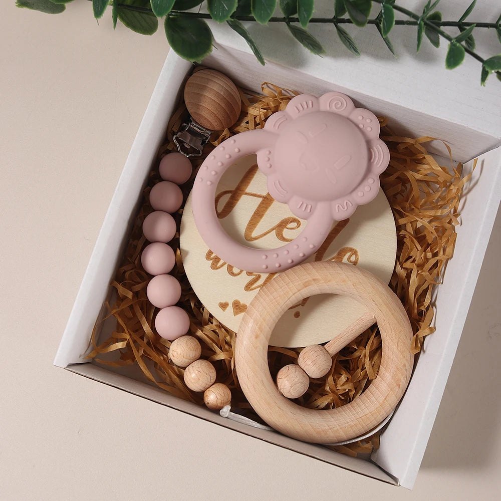 Baby teething ring set with pink silicone, wooden beads, and wooden ring in a decorative box.