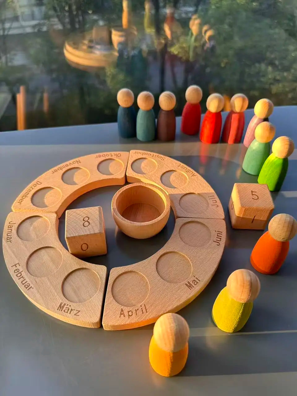 Wooden calendar with peg people and blocks on a reflective surface