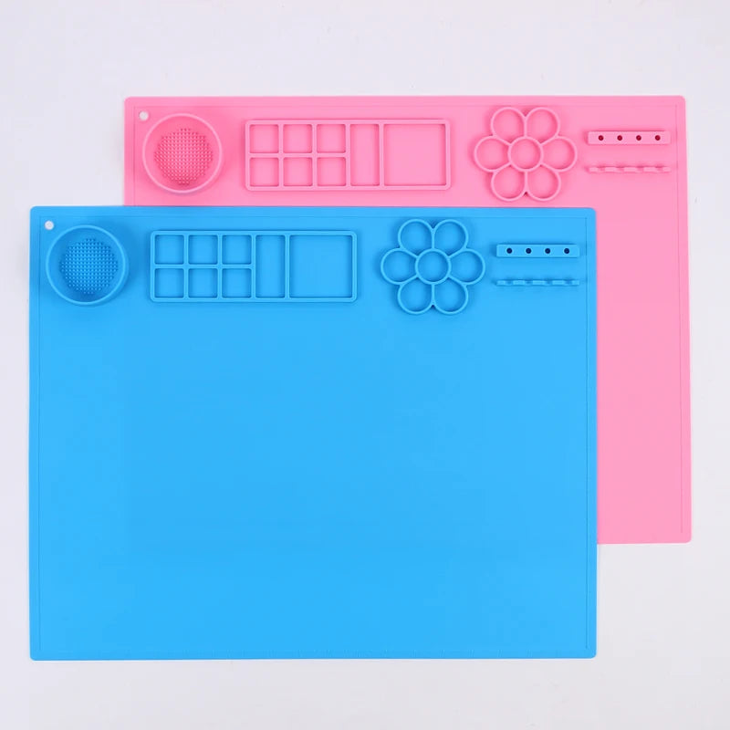 Two silicone mats, one blue and one pink, with various shapes and patterns on a light gray background.