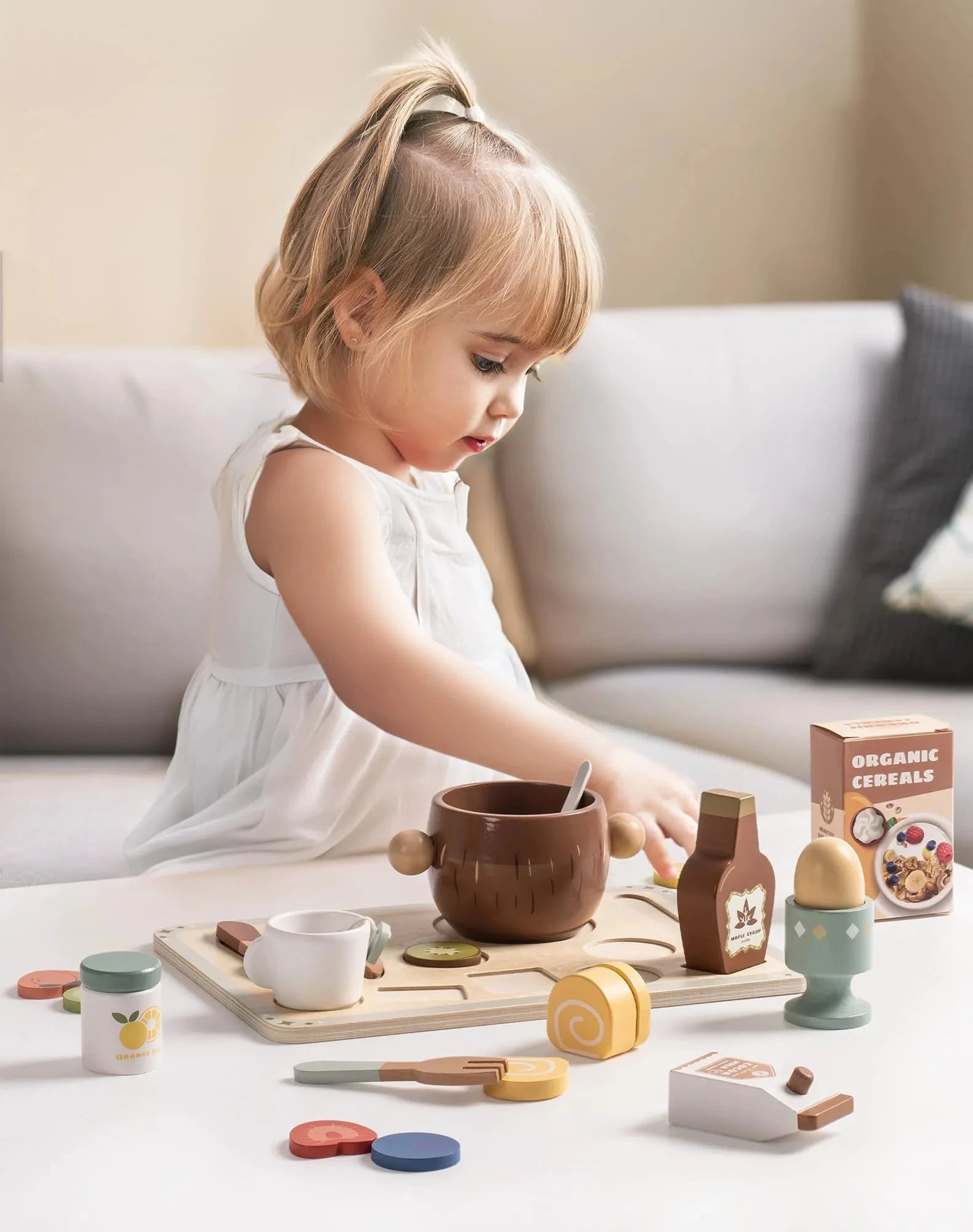 Child playing with a wooden toy kitchen set on a couch