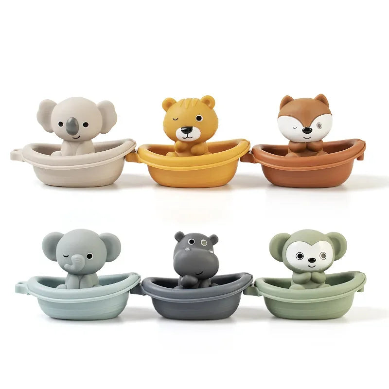 Six small animal-shaped bath toys arranged in two rows on a white background. The top row shows a beige koala, a yellow tiger, and a brown fox sitting in matching brown boats.