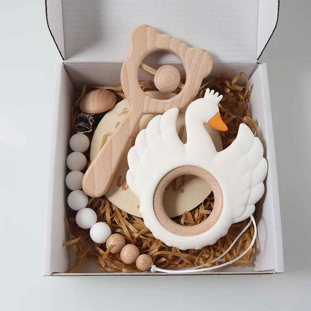 Baby teething toy set with wooden toys and a silicone swan in a box.