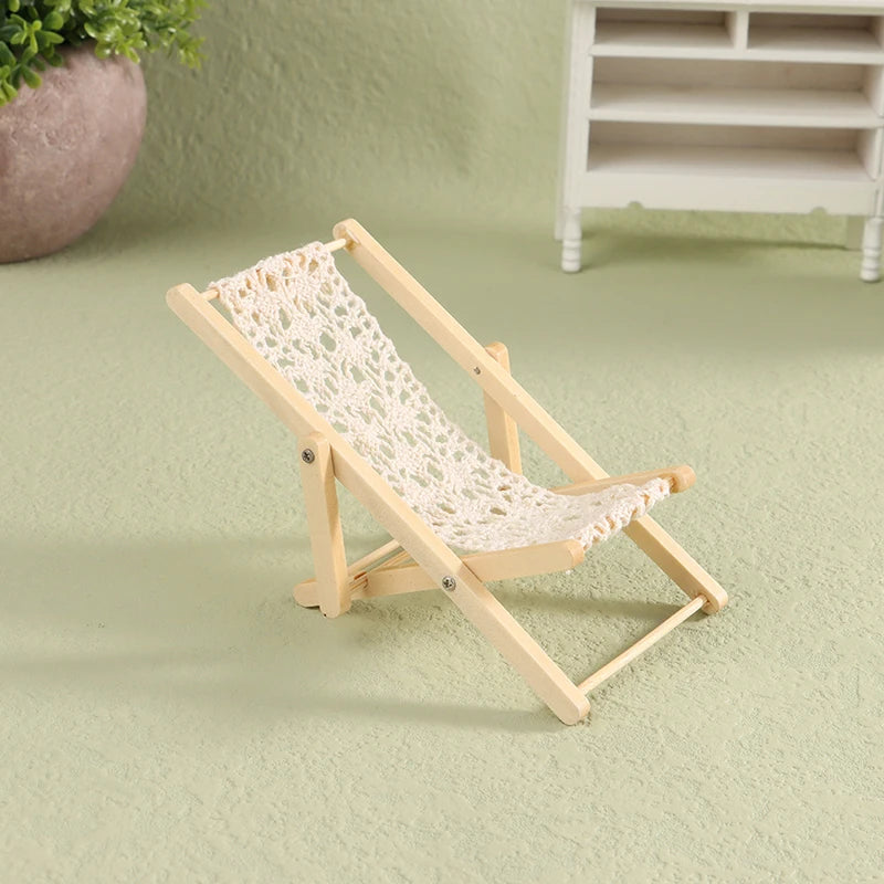 Miniature wooden deck chair with a woven seat on a light green surface. Oliver & Company Montessori Toys