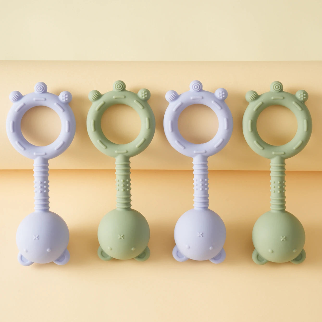 Two pairs of silicone baby teething rings on a yellow background