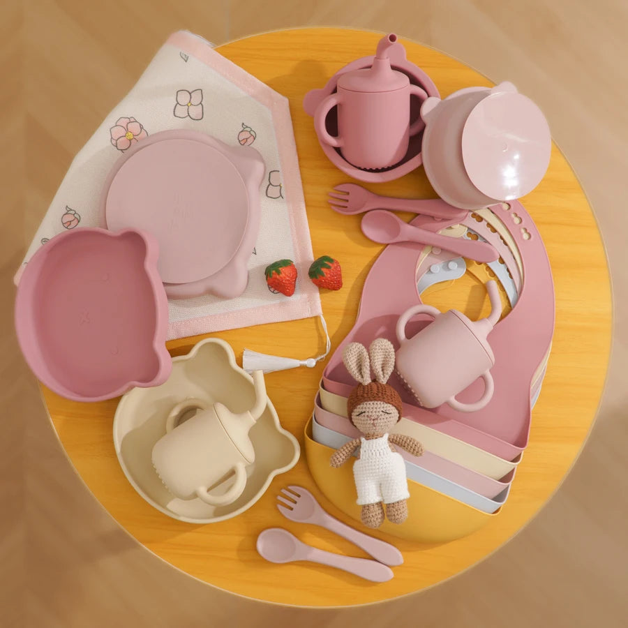 Collection of pink children's tableware and toys on a wooden surface