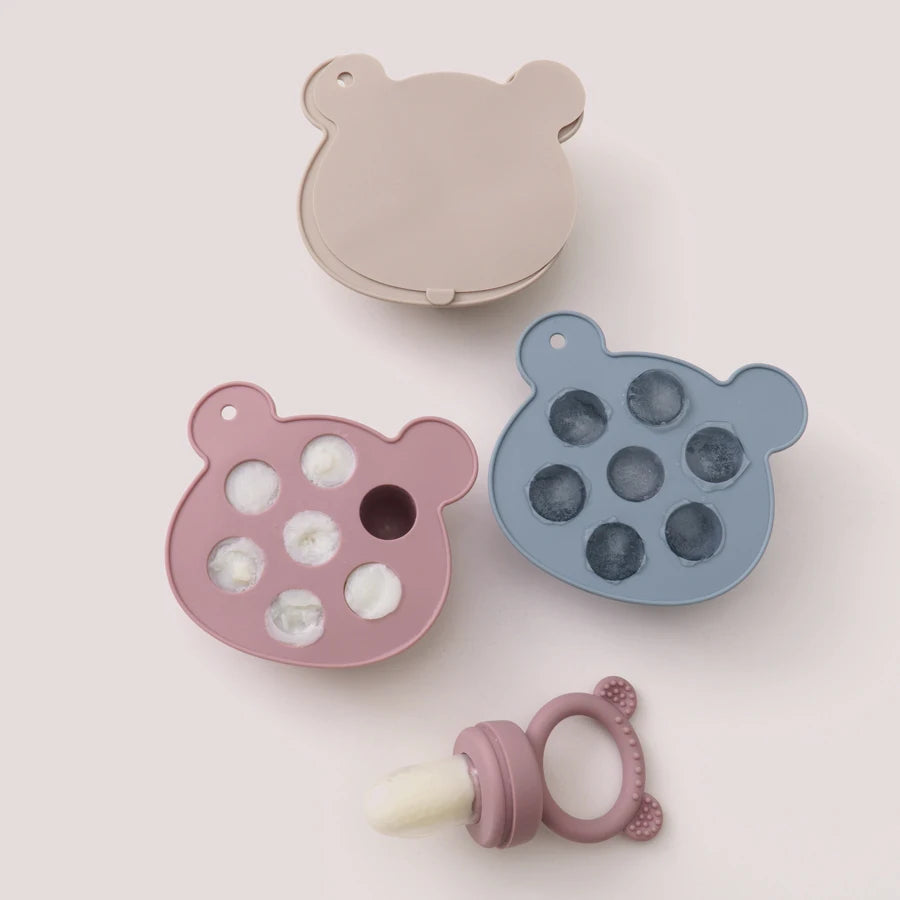 Bear-shaped silicone trays filled with frozen breast milk pops
