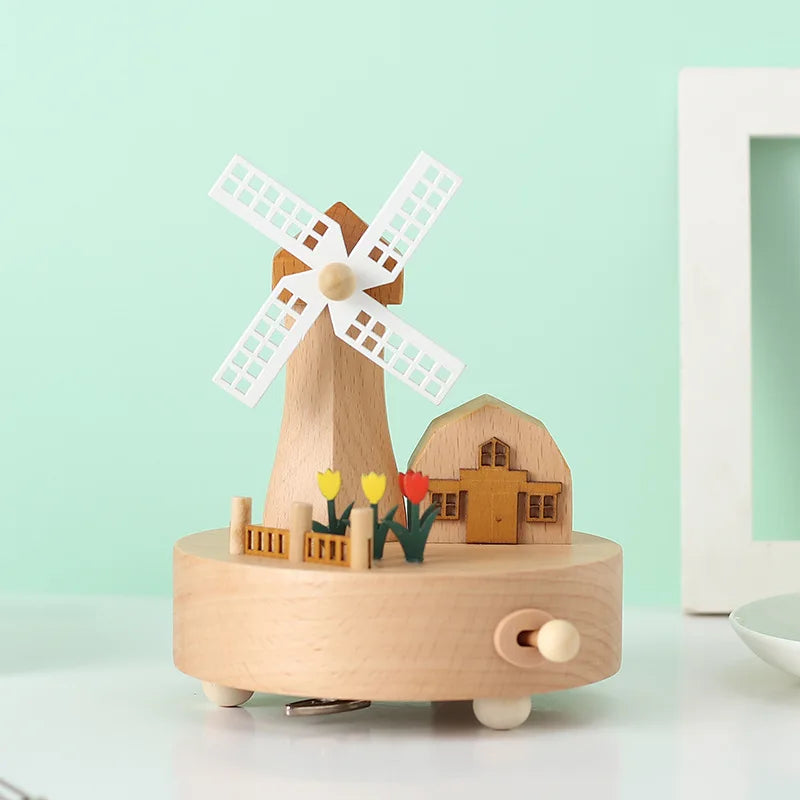 Wooden windmill music box with a small house and flowers on a light green background