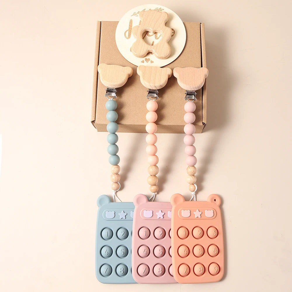 Three colorful baby teether toys with bear-shaped clips on a beige background