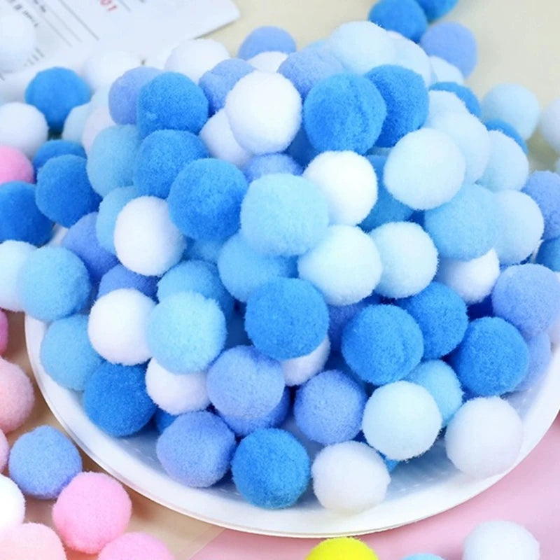 White plate with blue, white, and pink pom-poms on a light background