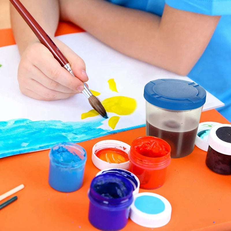 Child painting a sun with watercolors on an orange table.