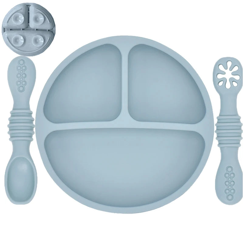 Silicone baby plate with divided sections and utensils on a white background