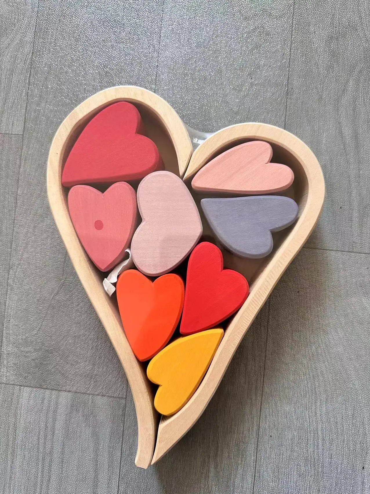 Heart-shaped wooden box with colorful heart-shaped blocks on a gray surface