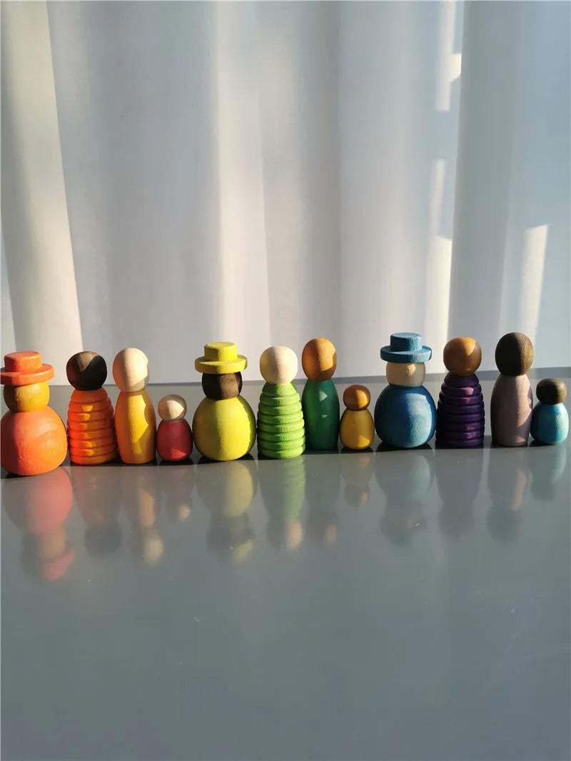 Colorful wooden peg dolls arranged in a row on a reflective surface with a white curtain background.