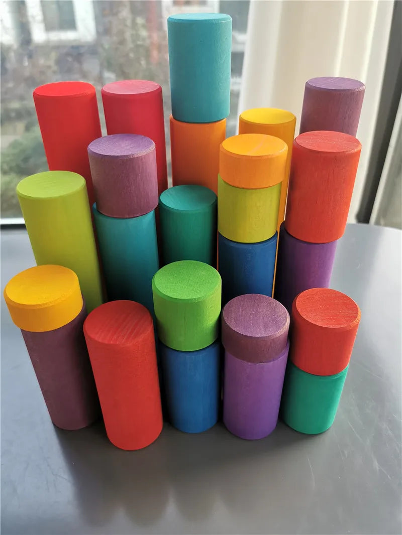 Stack of colorful cylindrical objects on a reflective surface with a window in the background