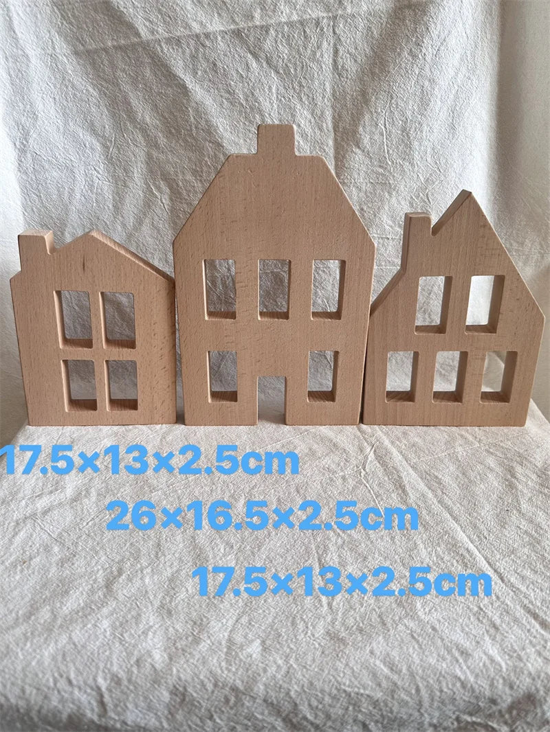 Three wooden house models of different sizes on a white fabric background