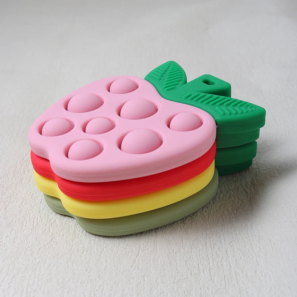 Stack of colorful pop-it fidget toys shaped like apples on a light gray background