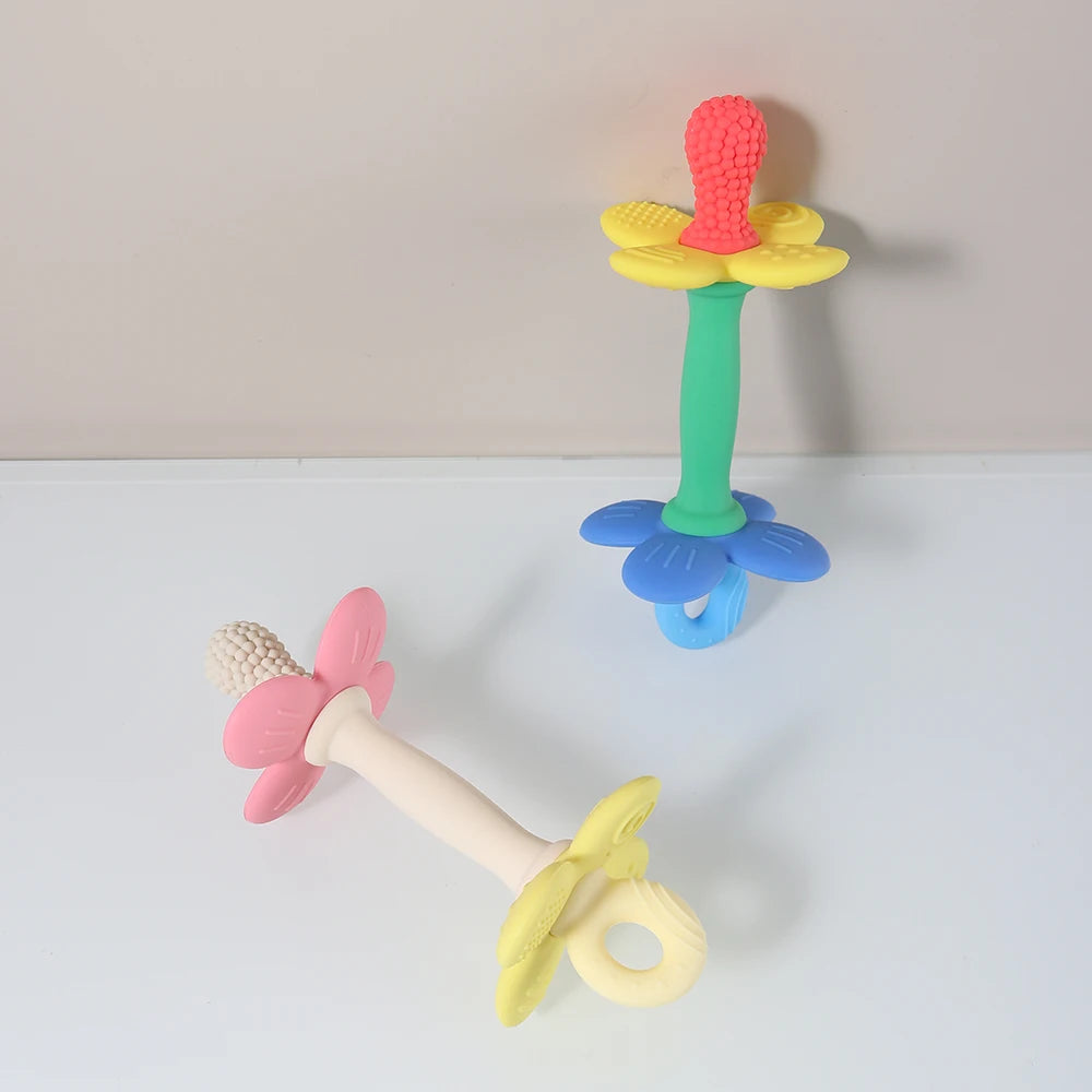 Colorful flower-shaped baby teether on a white surface with a beige background