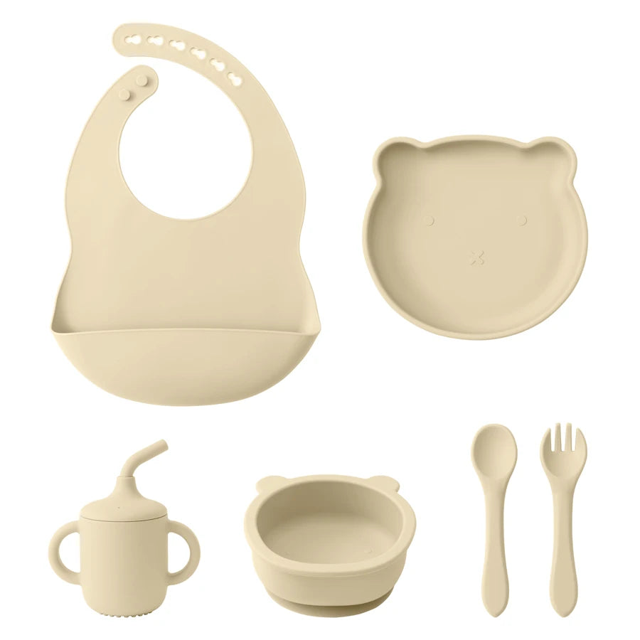 Set of baby feeding utensils including a bib, bowl, cup, spoon, and fork on a white background.