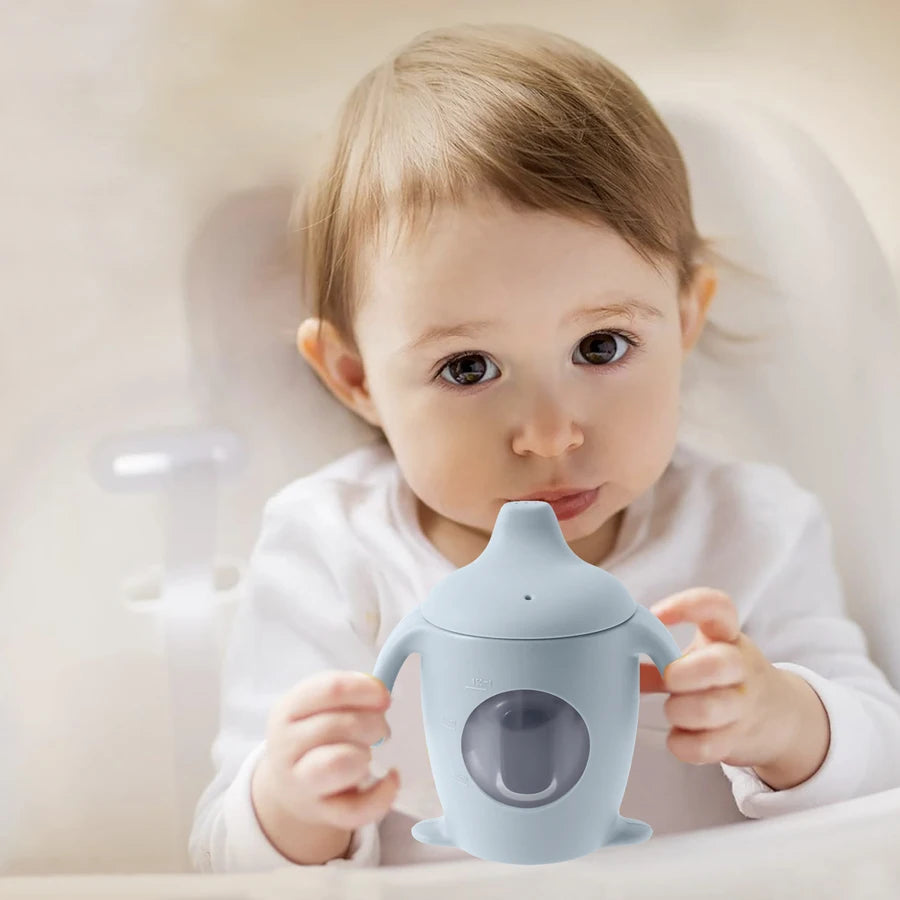 Baby holding a blue sippy cup against a neutral background