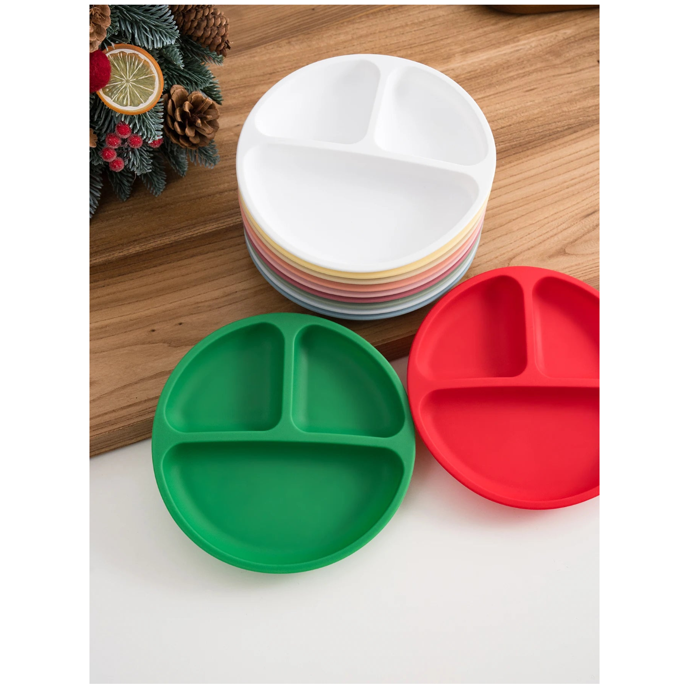 Red and green round silicone divided suction plates with a stack of white plates