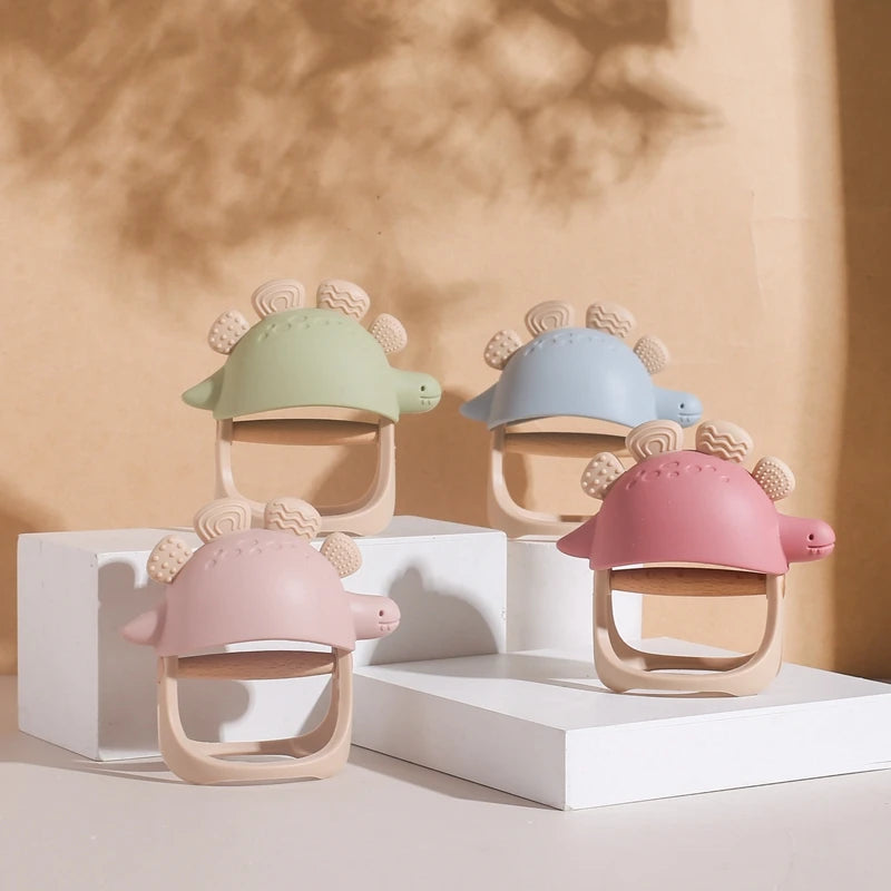 Three colorful dinosaur-shaped baby teething toys on a beige background