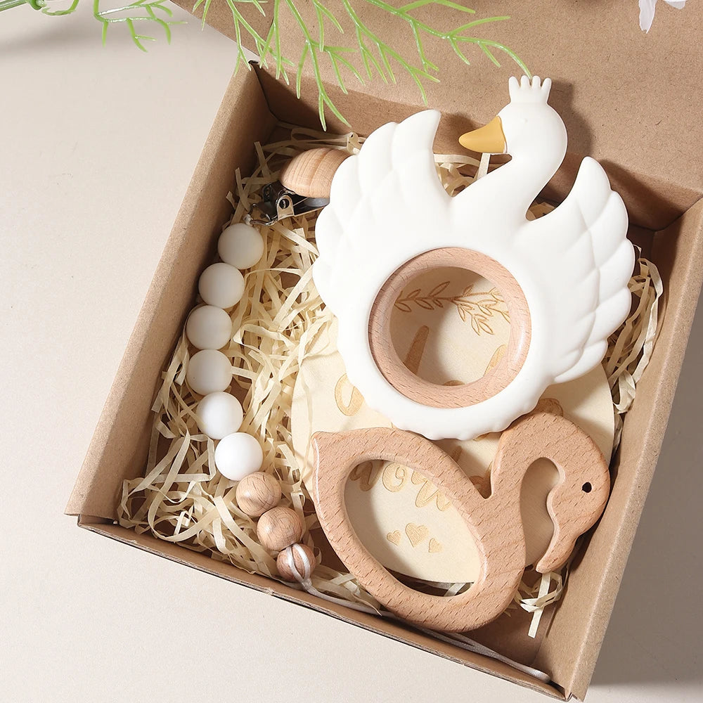 Swan-shaped baby teether set in a decorative box with natural elements.