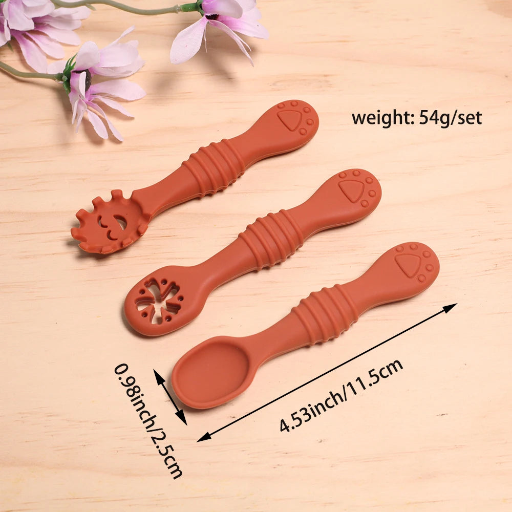 Three terracotta-colored ceramic spoons on a wooden surface with floral decorations.