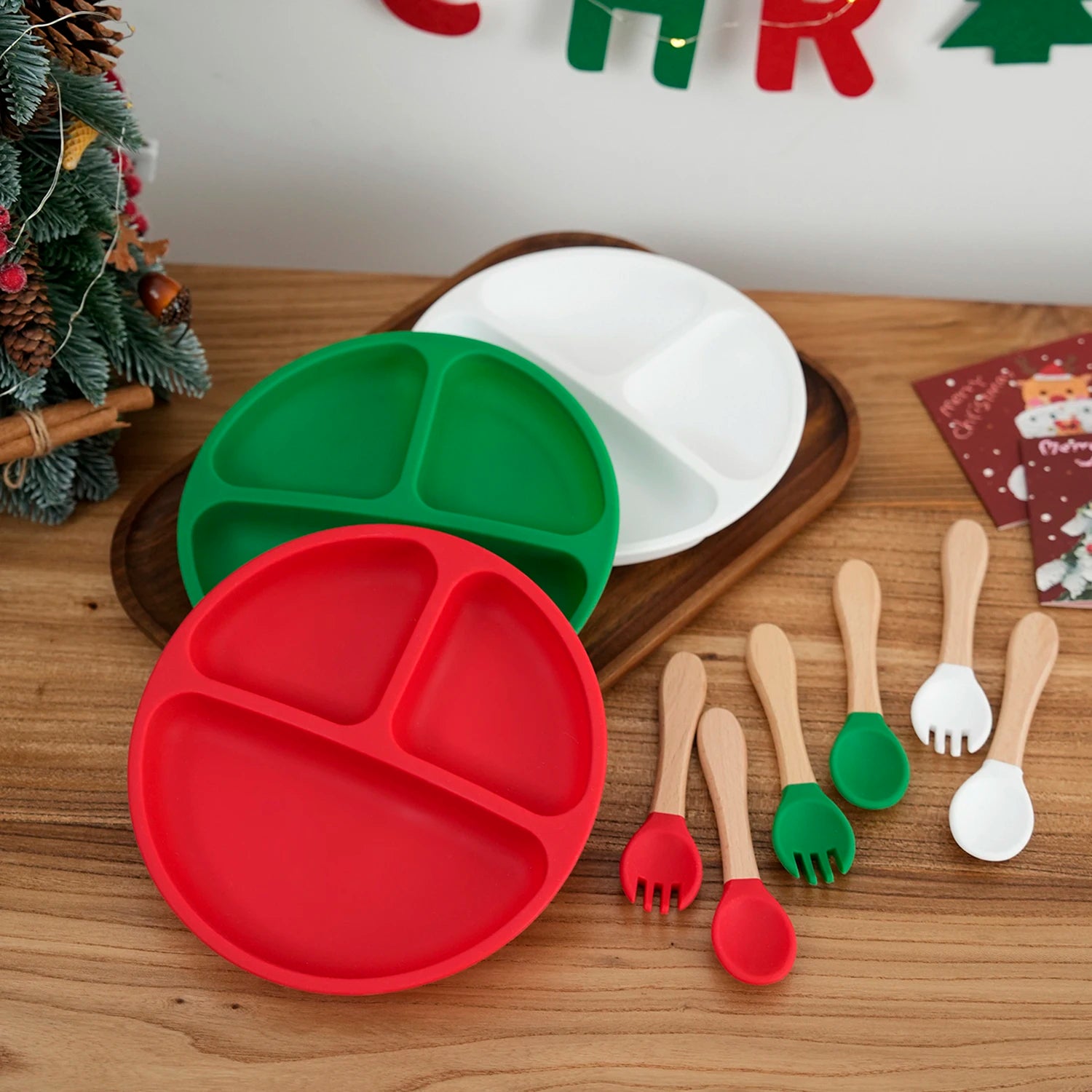Red, green and white silicone divided plates with wooden utensils on a holiday table