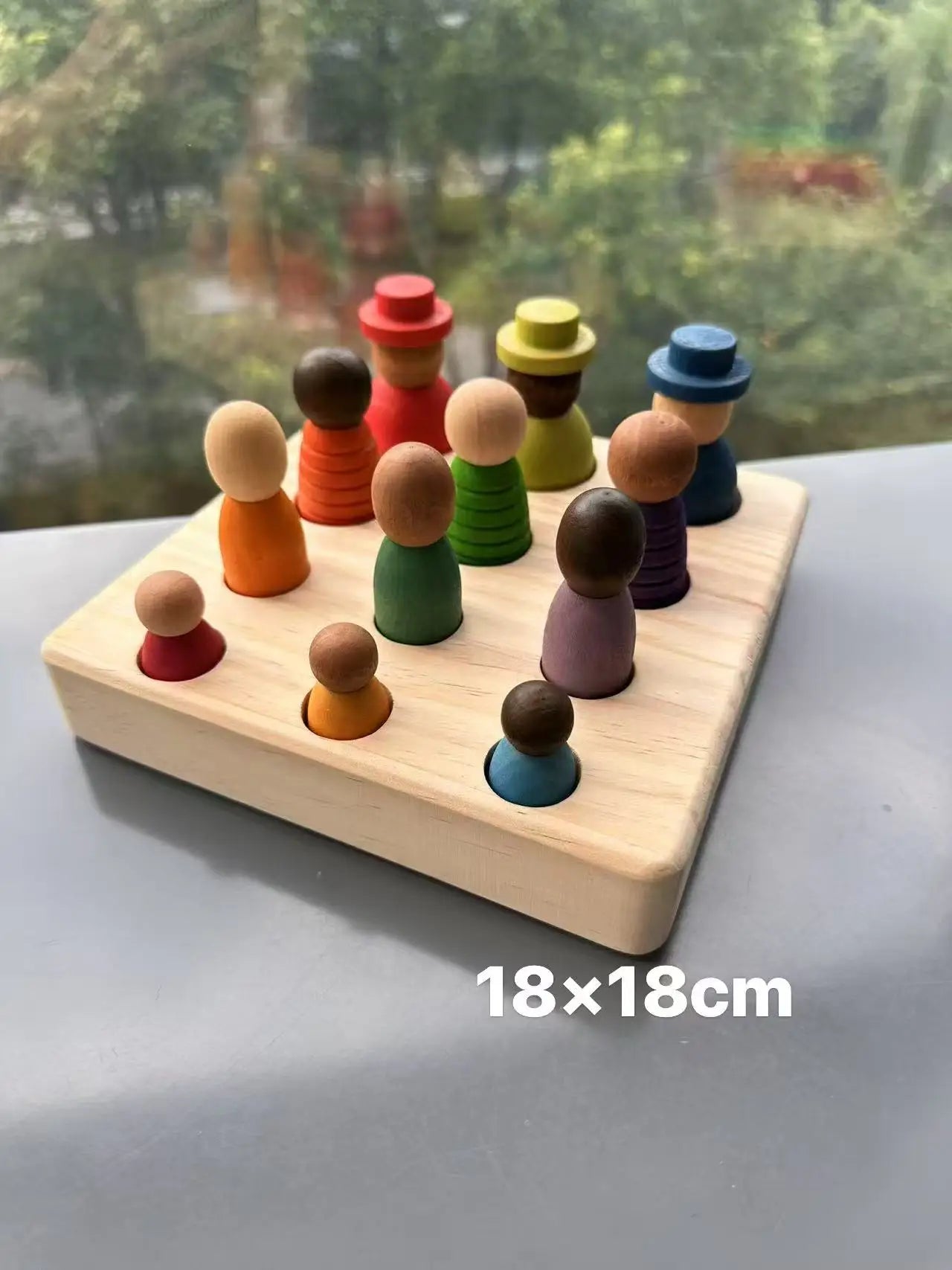 Colorful wooden peg people on a wooden board with a blurred outdoor background