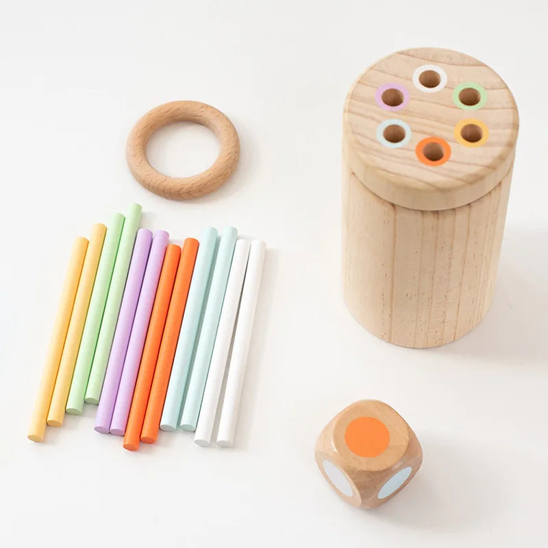 Set of wooden toys including a ring, dice, and colorful sticks on a white background