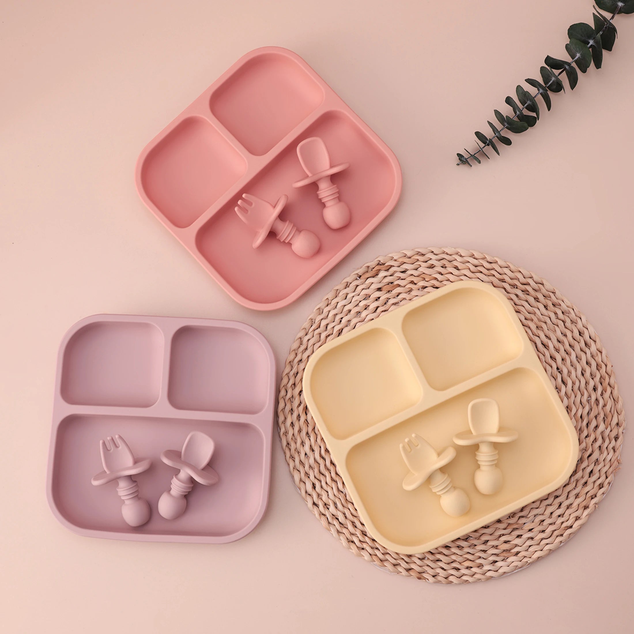 Set of children's silicone plates and utensils on a pink background