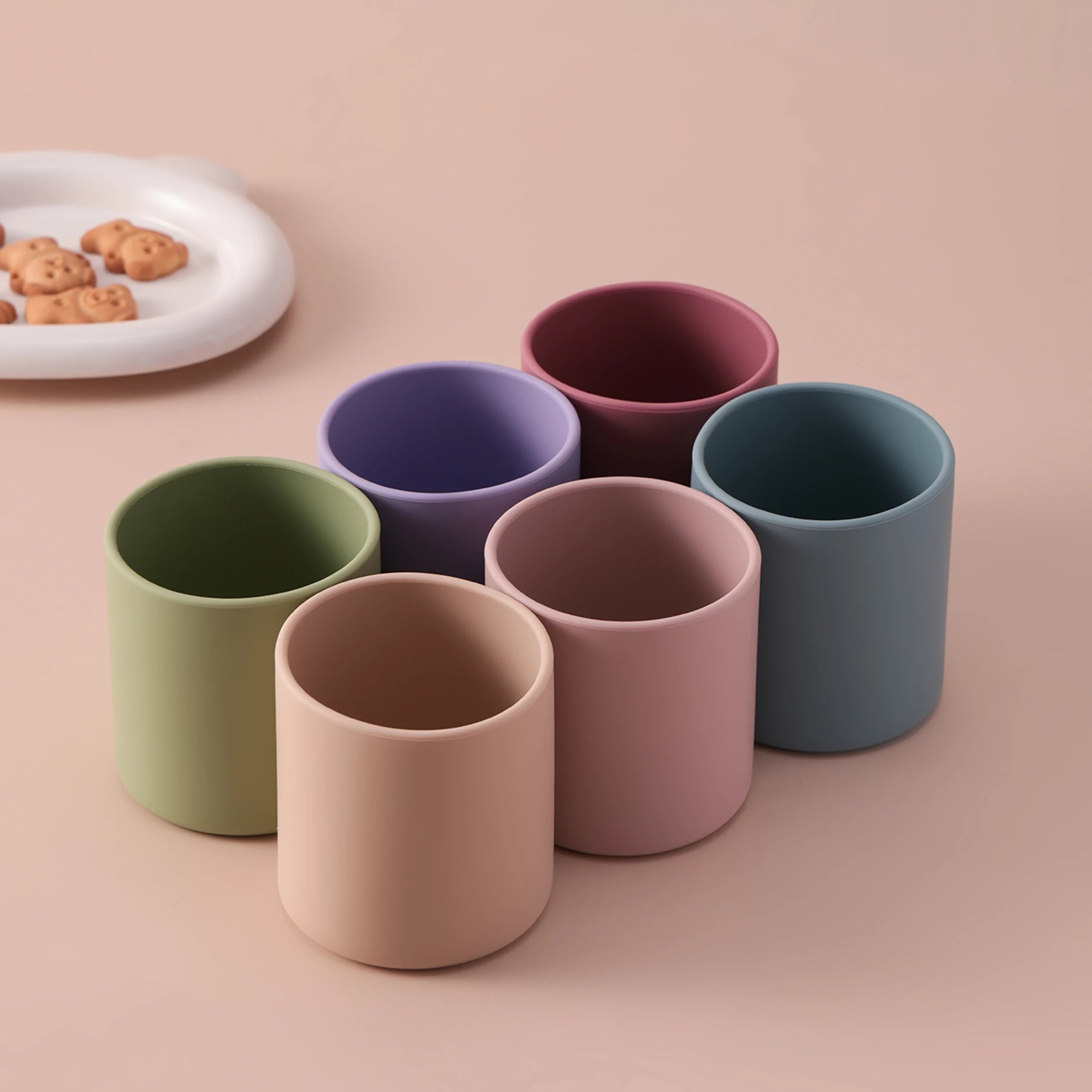 Silicone training cups in lavender, rose and sage on a pink background