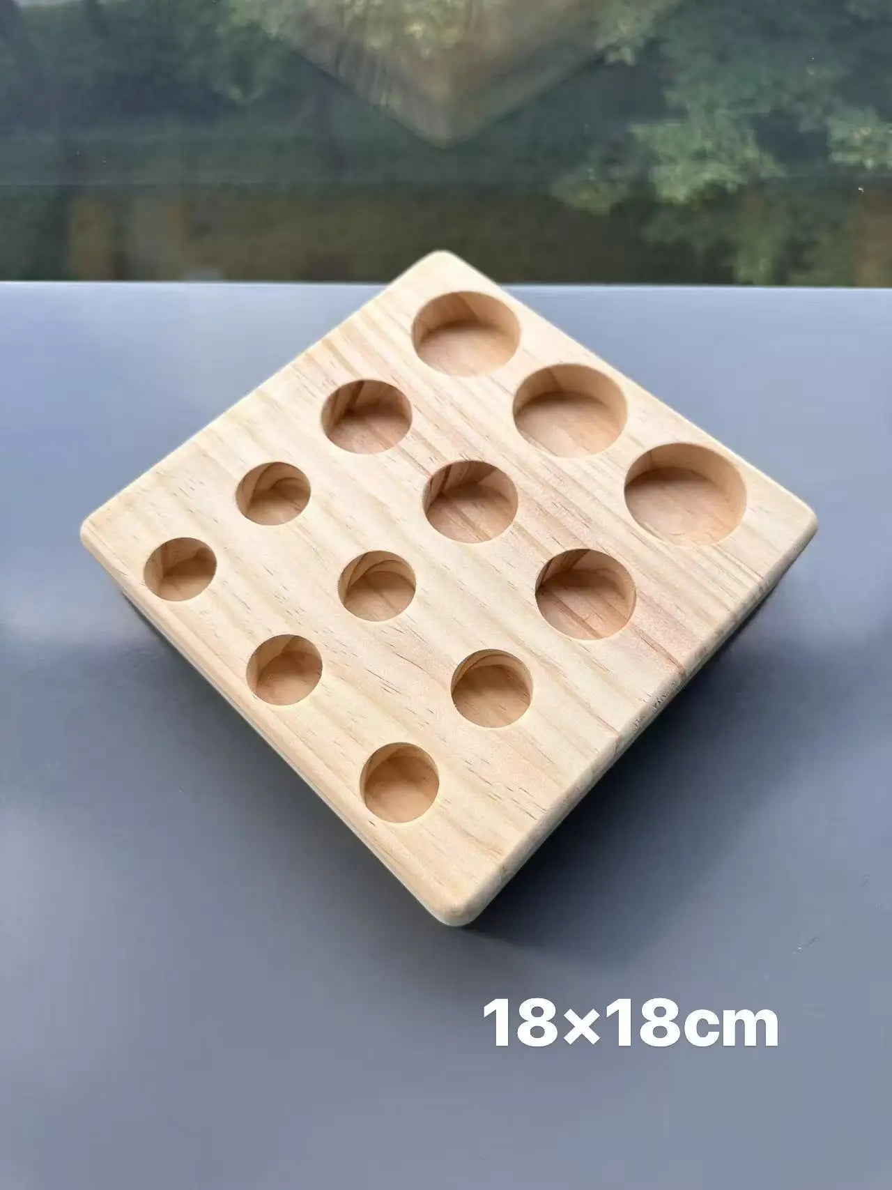 Wooden square block with multiple holes on a reflective surface