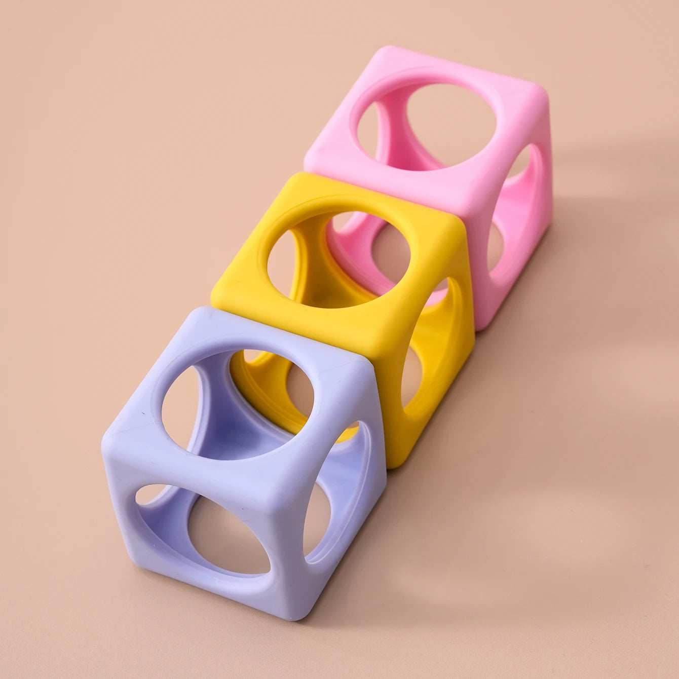 Lavender, yellow and pink silicone cube teethers in a row
