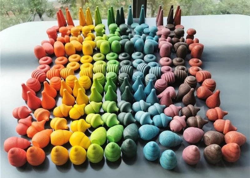 Colorful loose parts collection arranged in a circular pattern on a reflective surface.