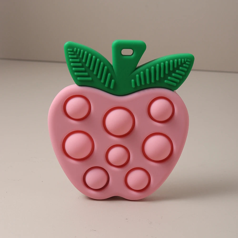 Pink apple-shaped pop-it toy with green stem on a beige background