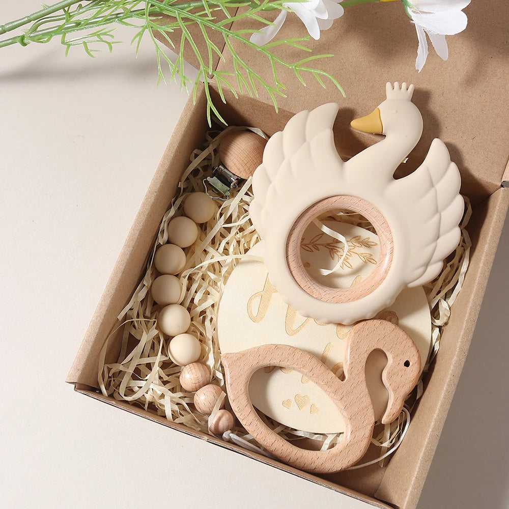 Set of swan-shaped wooden and ceramic baby teething toys in a box with decorative elements.