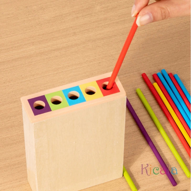 Wooden peg puzzle with colorful sticks on a wooden surface, featuring the brand 'Kicada'.