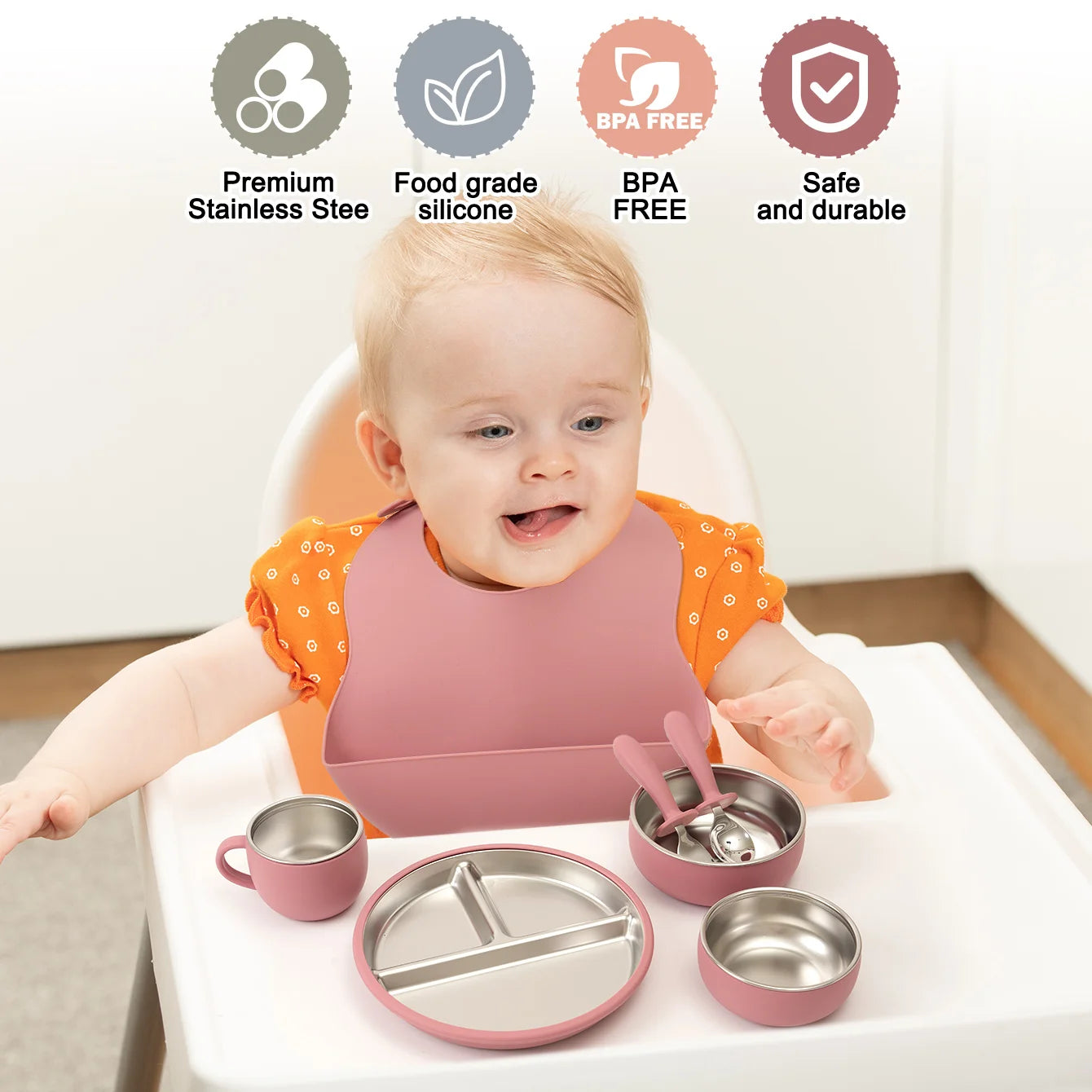 Baby sitting in a high chair with pink and silver吃饭ware, including a bowl, cup, and spoon.