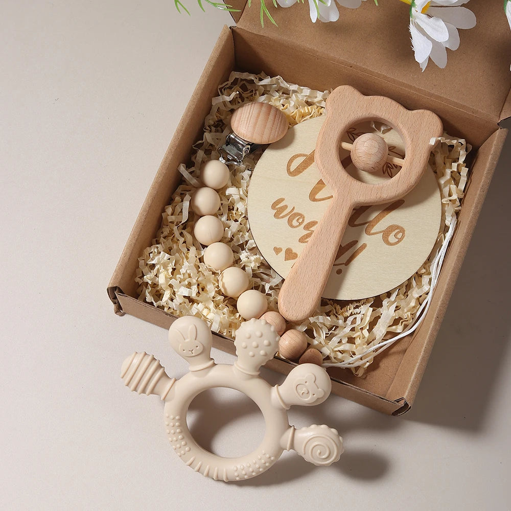 Wooden baby rattle and teether set in a gift box with decorative flowers.