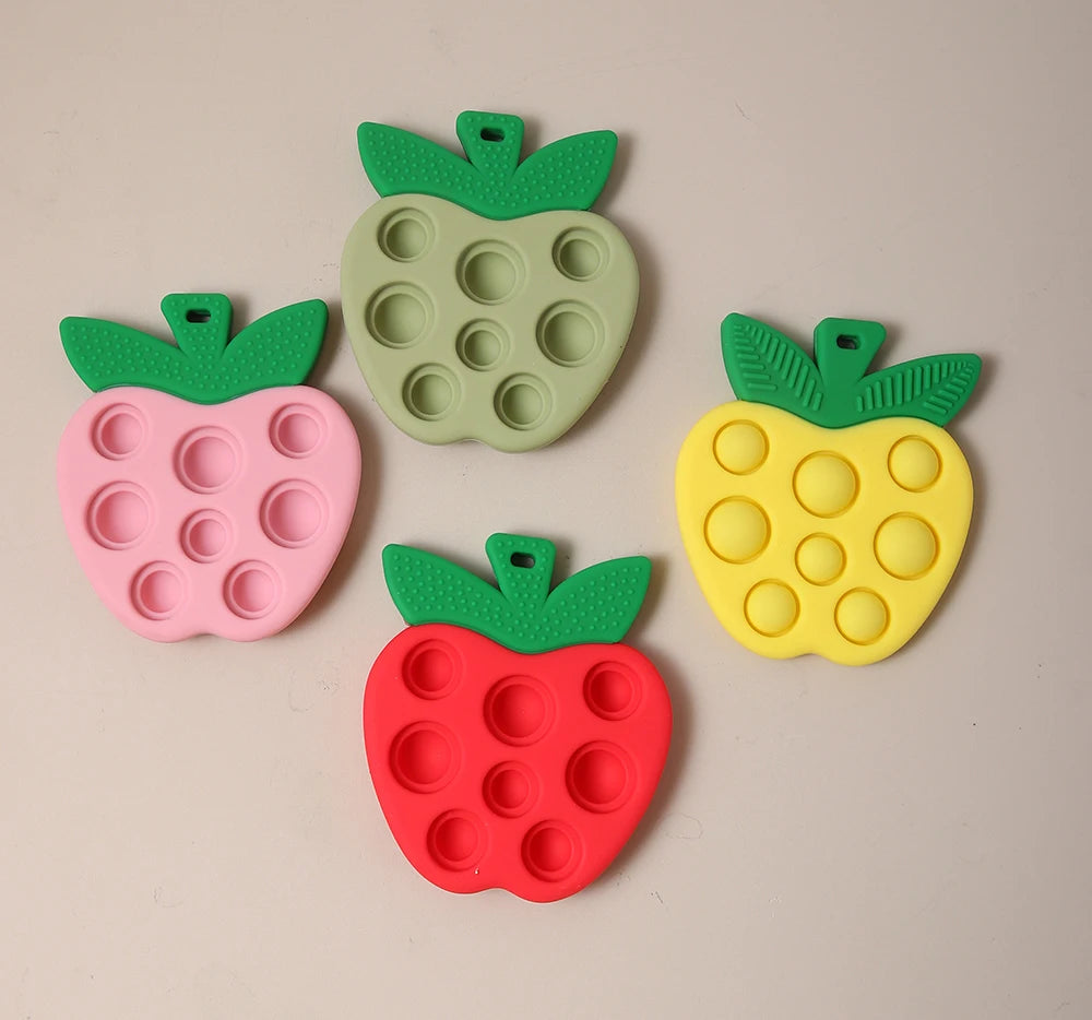 Four colorful pop-it toys shaped like strawberries on a beige background