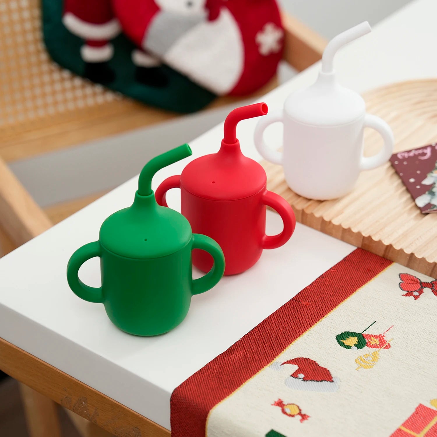 Green, red and white silicone straw cups on a Christmas table runner
