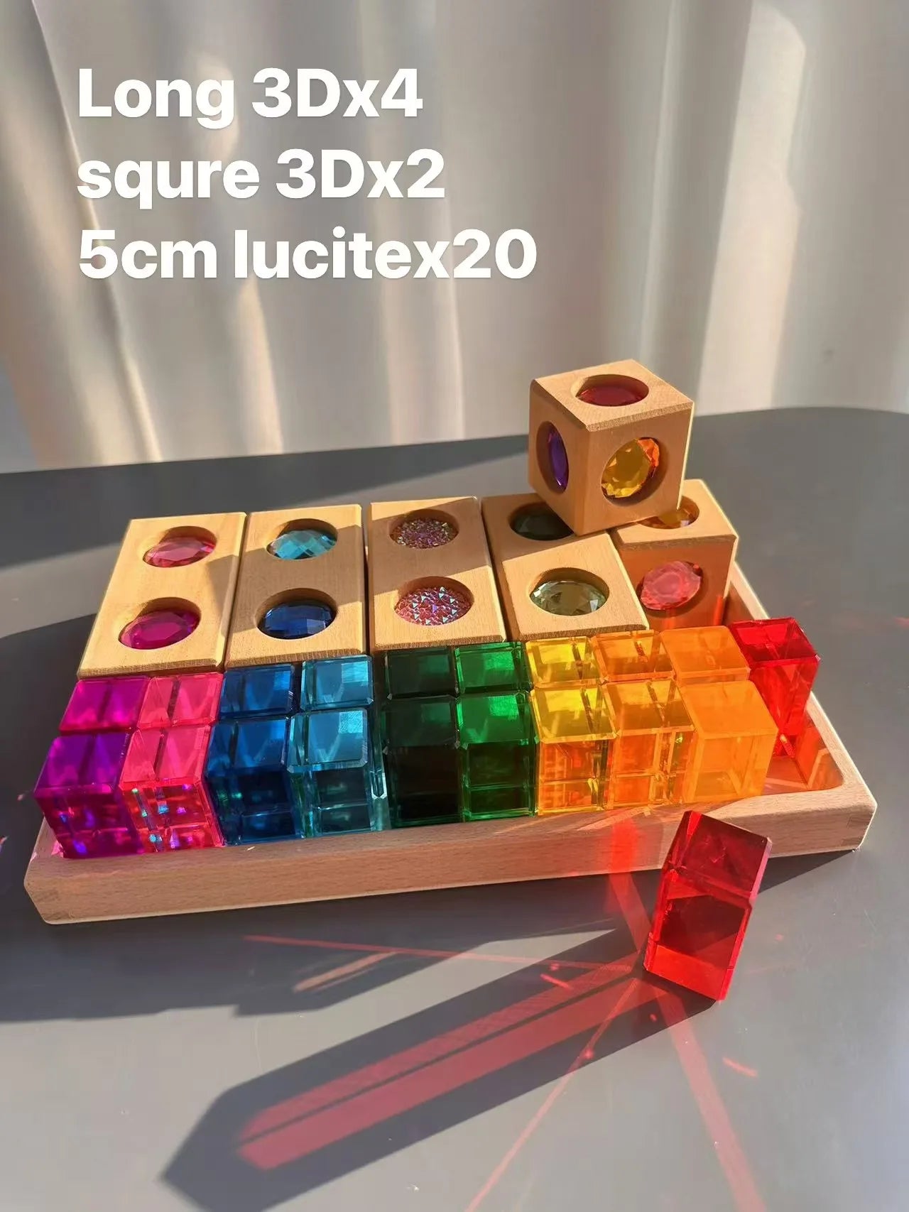 Colorful transparent building blocks in a wooden holder on a gray surface.