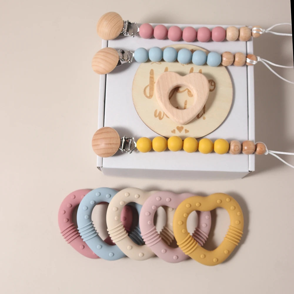 Set of colorful baby teething rings and pacifier clips on a beige background