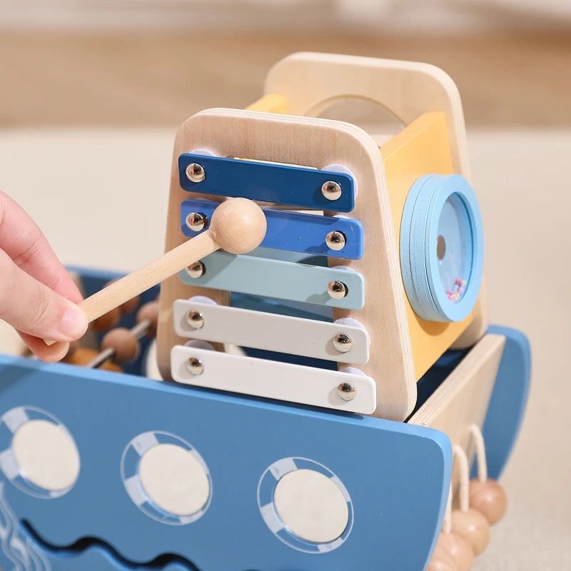 Wooden toy xylophone with colorful keys and a stick, held by a hand against a neutral background.