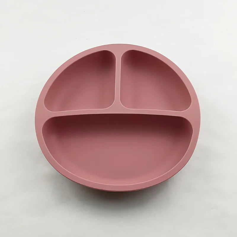Pink silicone plate with divided sections on a white background