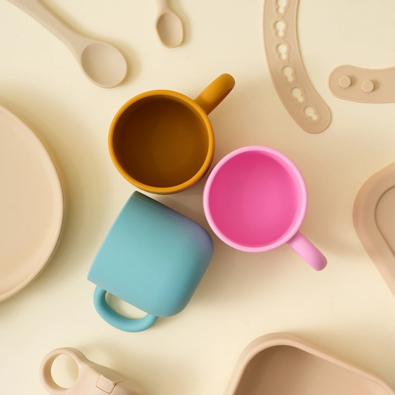 Blue, mustard and pink silicone toddler mugs on a table