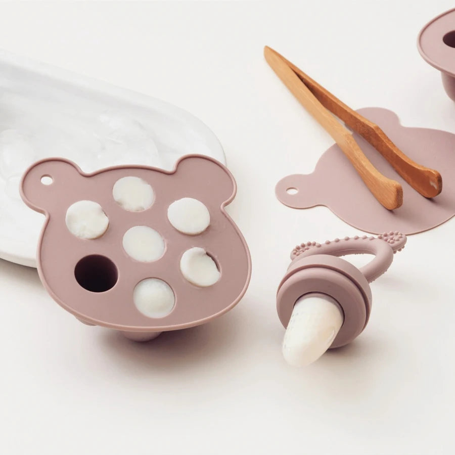 Pink popsicle tray with tongs and a milk pop in the feeder
