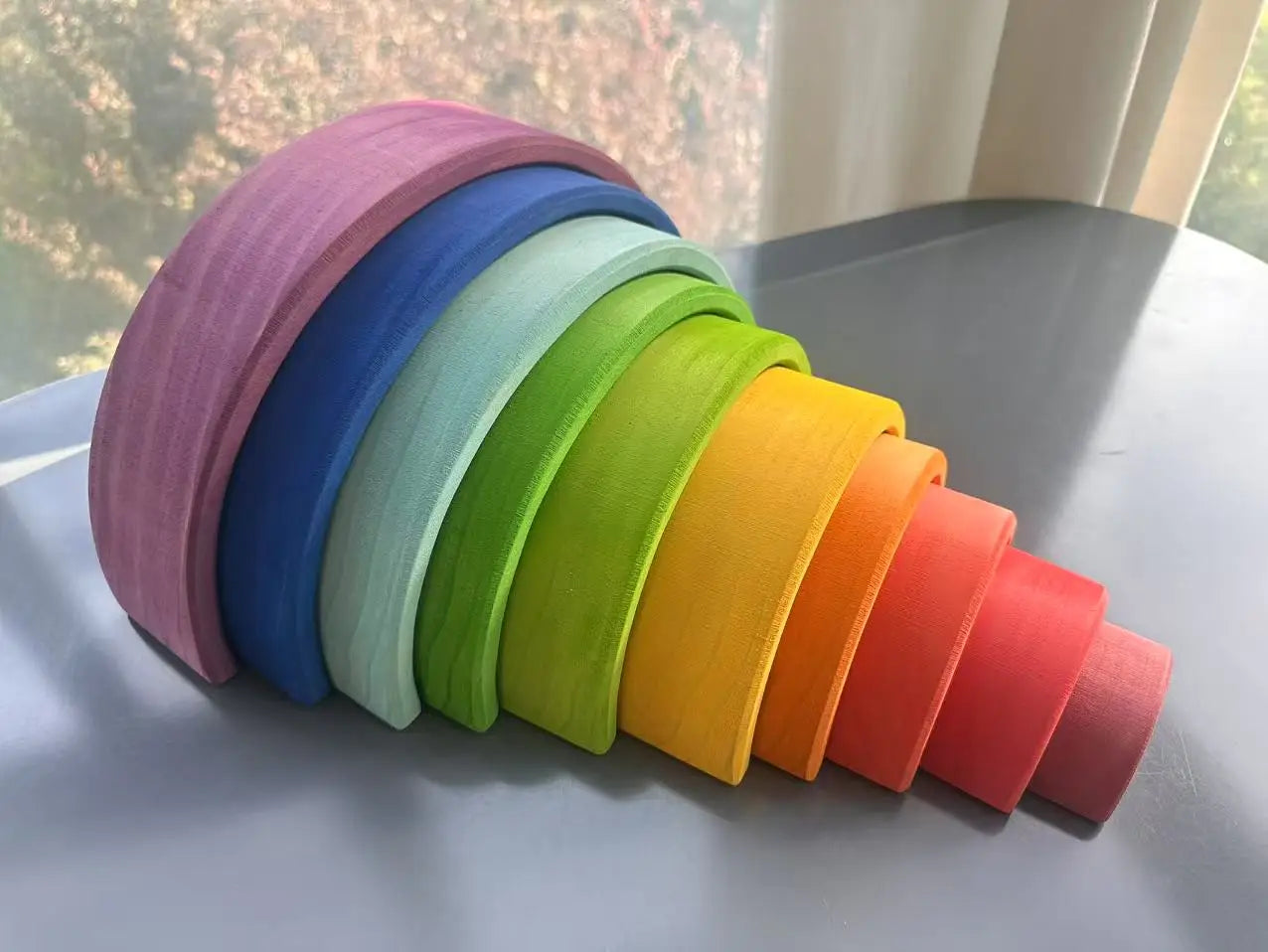 Stack of colorful wooden arches on a flat surface with a blurred natural background